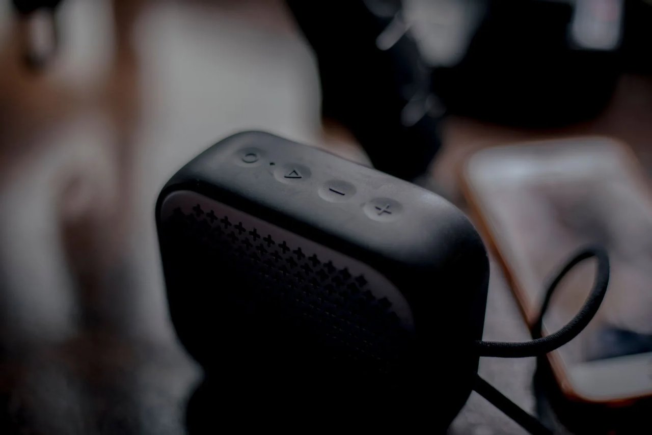 Black Boom Mini Bluetooth speaker next to a phone